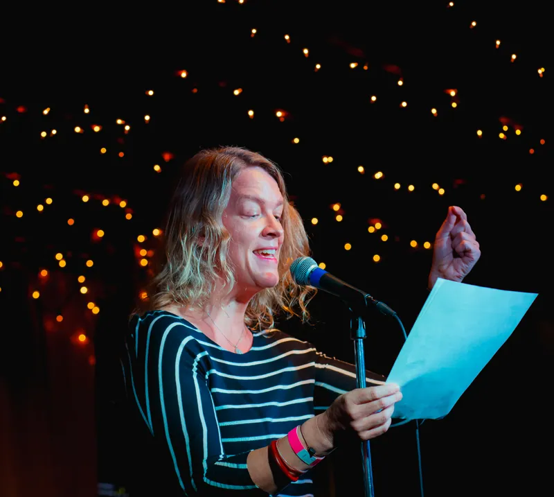 A combatant reading from a blue page under strings of lights