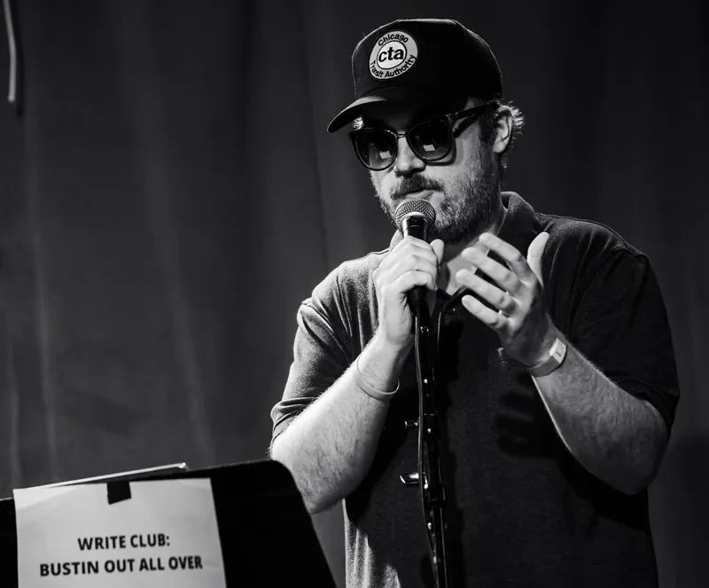 A combatant in a cap and sunglasses at the microphone, in black and white