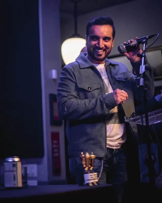A combatant grinning with the microphone raised, the Loving Cup in front of him